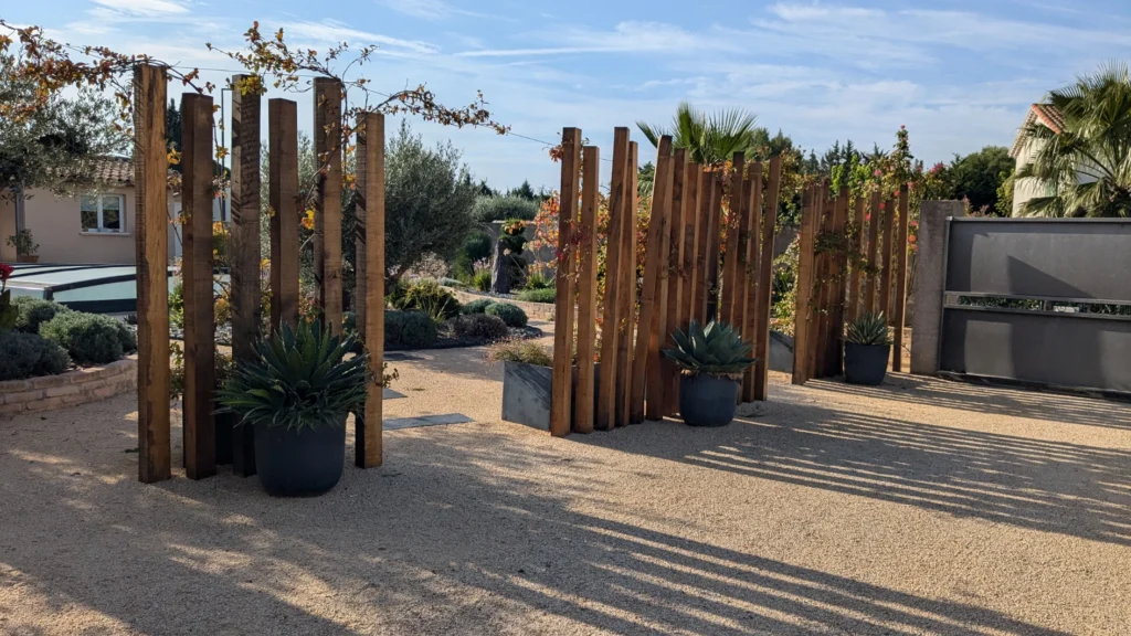 Aménagement d'une cour avec des traverses de chenes paysagères, des grimpantes et massif méditerranéens côté piscine.